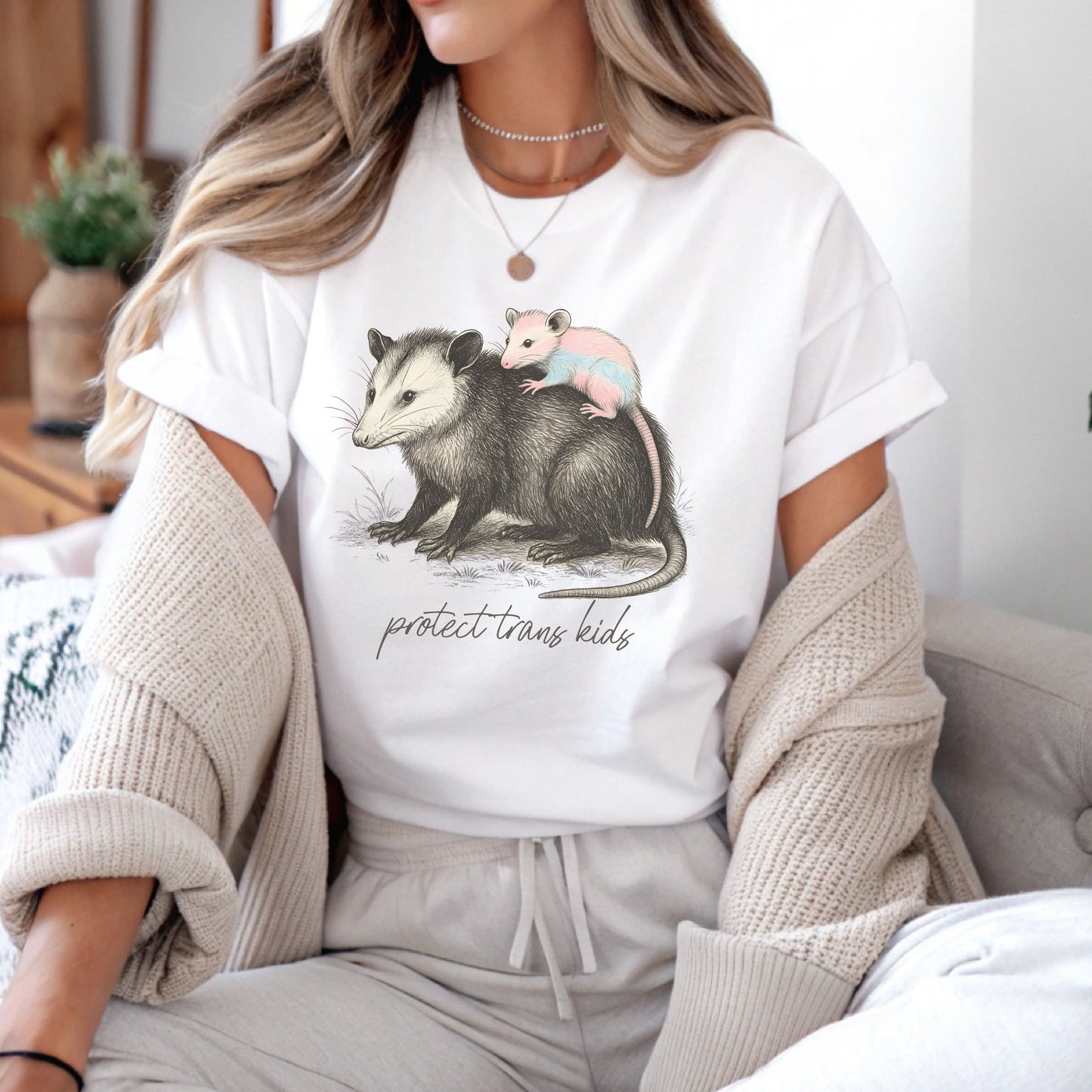 Person wearing a white t-shirt with an illustration of an opossum and two baby opossums, sitting on a couch: Protect Trans Kids Shirt, Transgender Pride Tee, Cute Opossum Tee, Fight Trans Rights, FTM MTF Mom Ally Gift, LGBT Support Outfit, Mama Bear