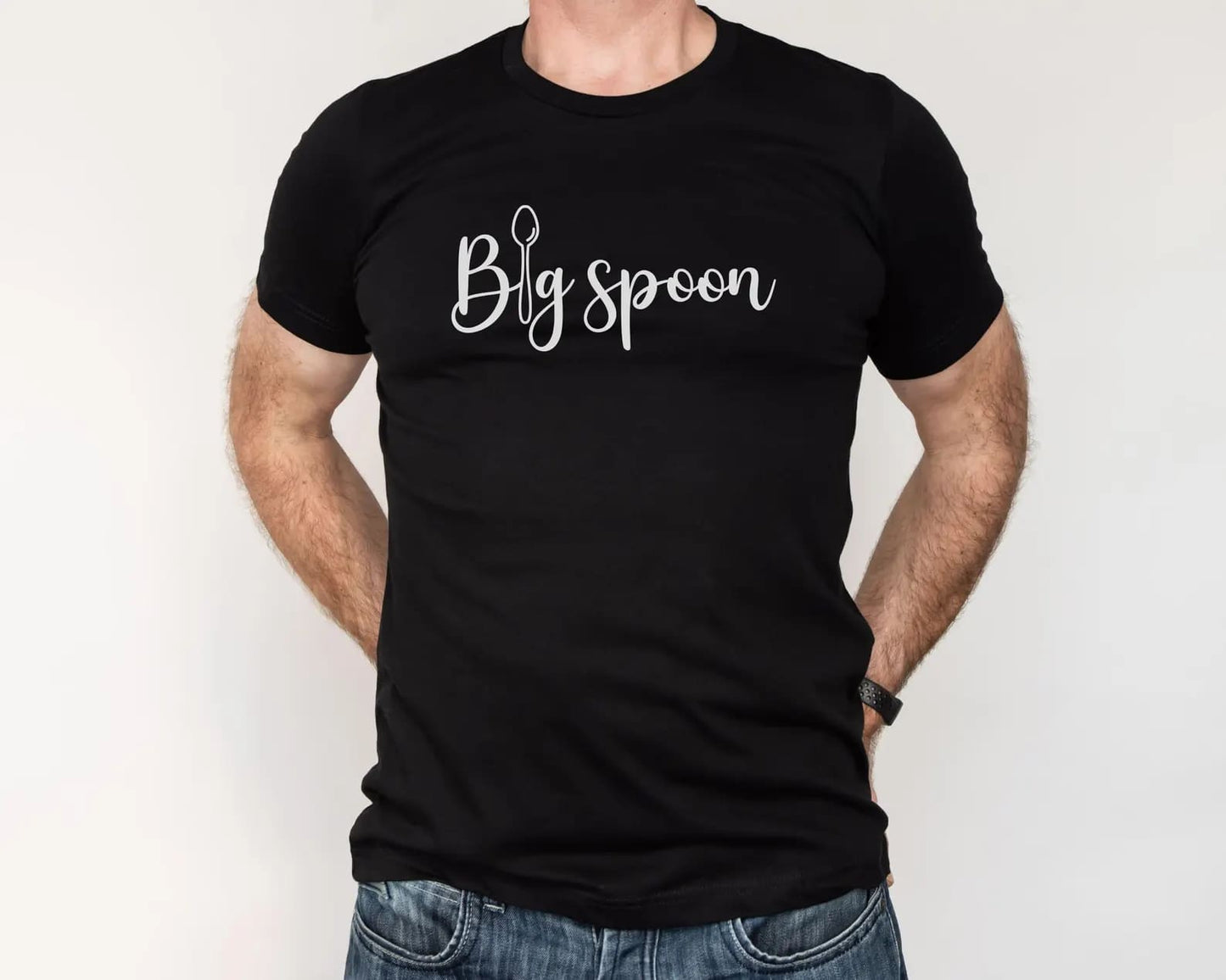 Polyamorous person wearing a black t-shirt with 'Big spoon' ENM text on a plain background
