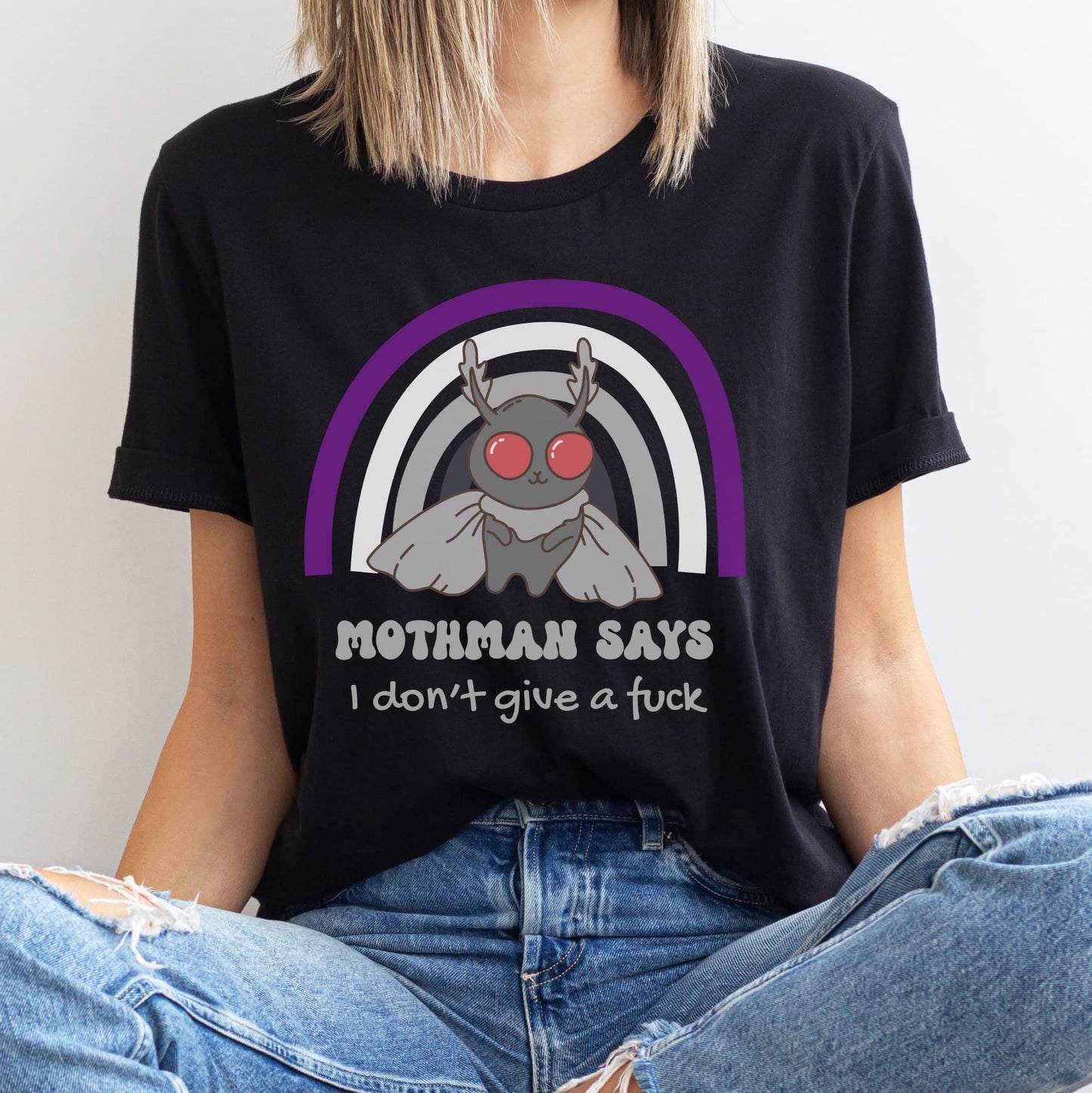 Person wearing a black t-shirt with a graphic design and text, sitting against a plain background: Asexual Mothman Shirt, Funny Ace Pride Cryptid Tee, Folklore Mythology T-Shirt, Queer Cryptozoology Gift, Cryptidcore Weird Stuff, LGBTQ