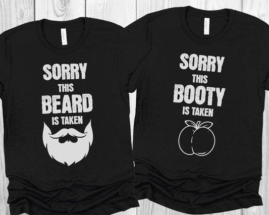 Two black t-shirts with cheesy naughty humor and graphics on a wooden surface.