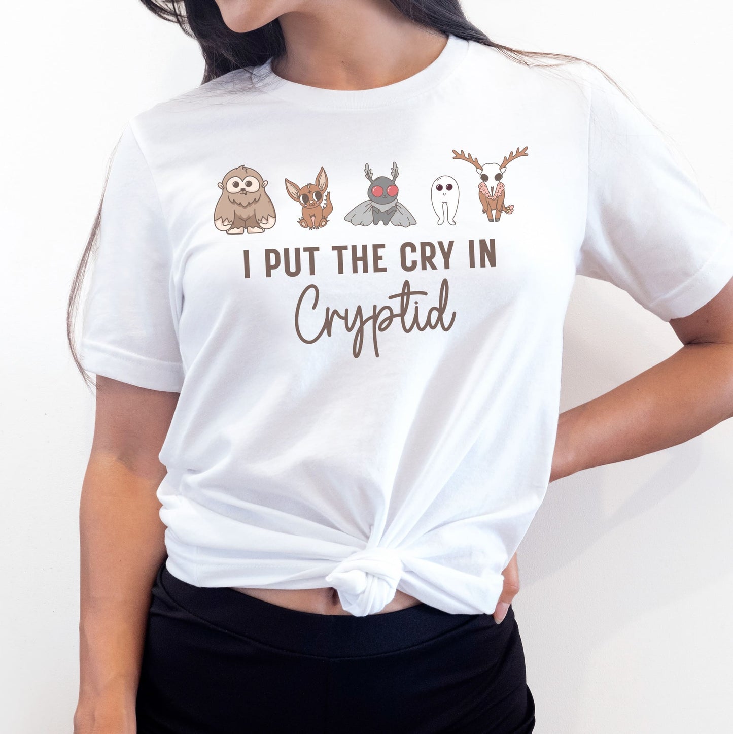 Person wearing a white t-shirt with cryptid creature illustrations and text: Funny Cryptid Mental Health Awareness Comfort Colors Shirt, Cute Cryptidcore Neurodivergent Tee, Kawaii Cryptozoology Neurospicy T-Shirt