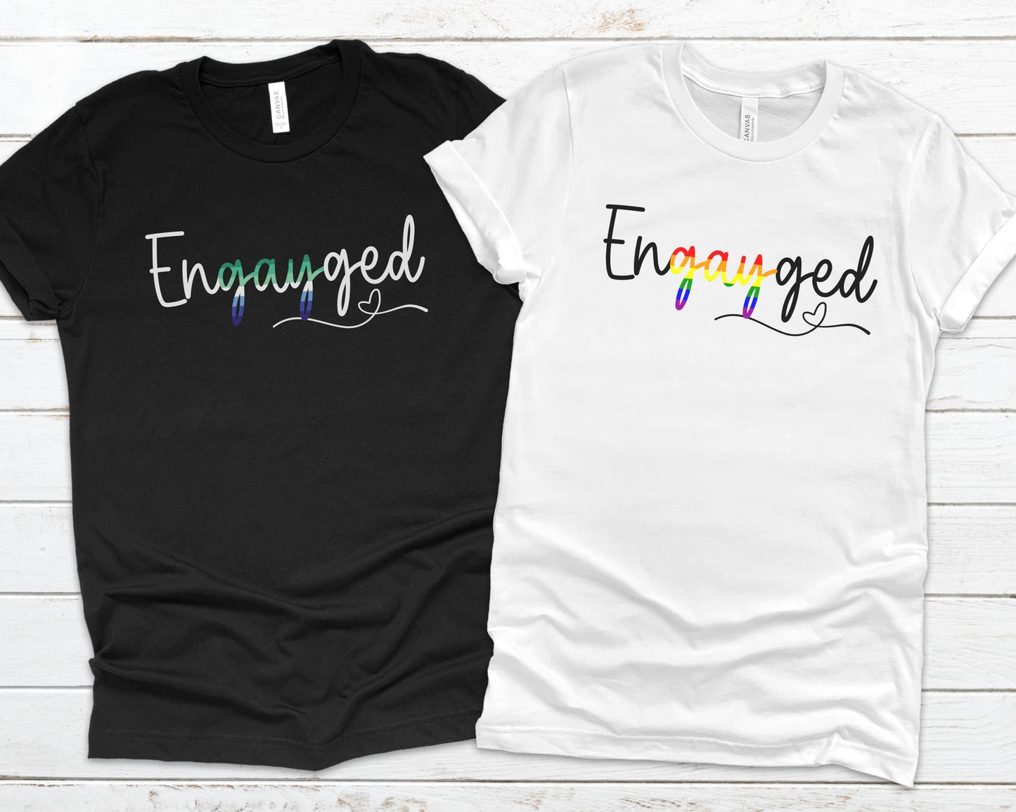 Black and white gay MLM engagement t-shirts with 'Engayged' text on a wooden surface