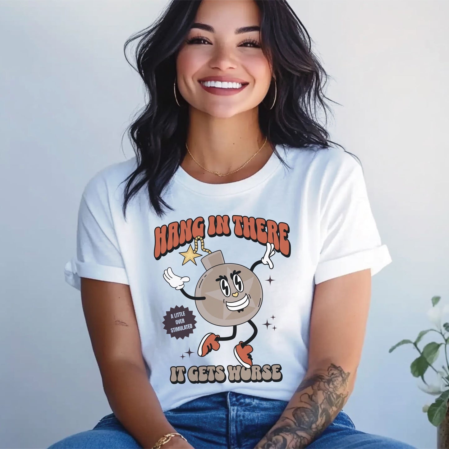 Person wearing a white t-shirt with a cartoon character and text against a plain background: Funny Overstimulated Shirt, Sarcastic Mental Health Tee, Retro Y2K Meme T-Shirt, Snarky Neurospicy Anxiety Gift, Hang In There It Gets Worse