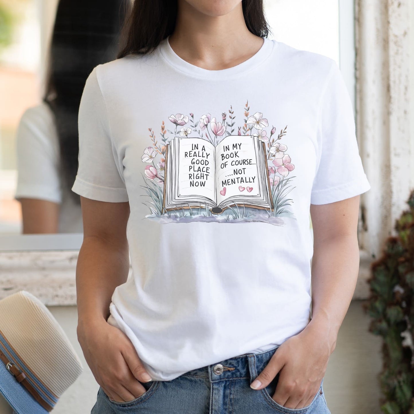 Person wearing a white t-shirt with a book-themed design and text.