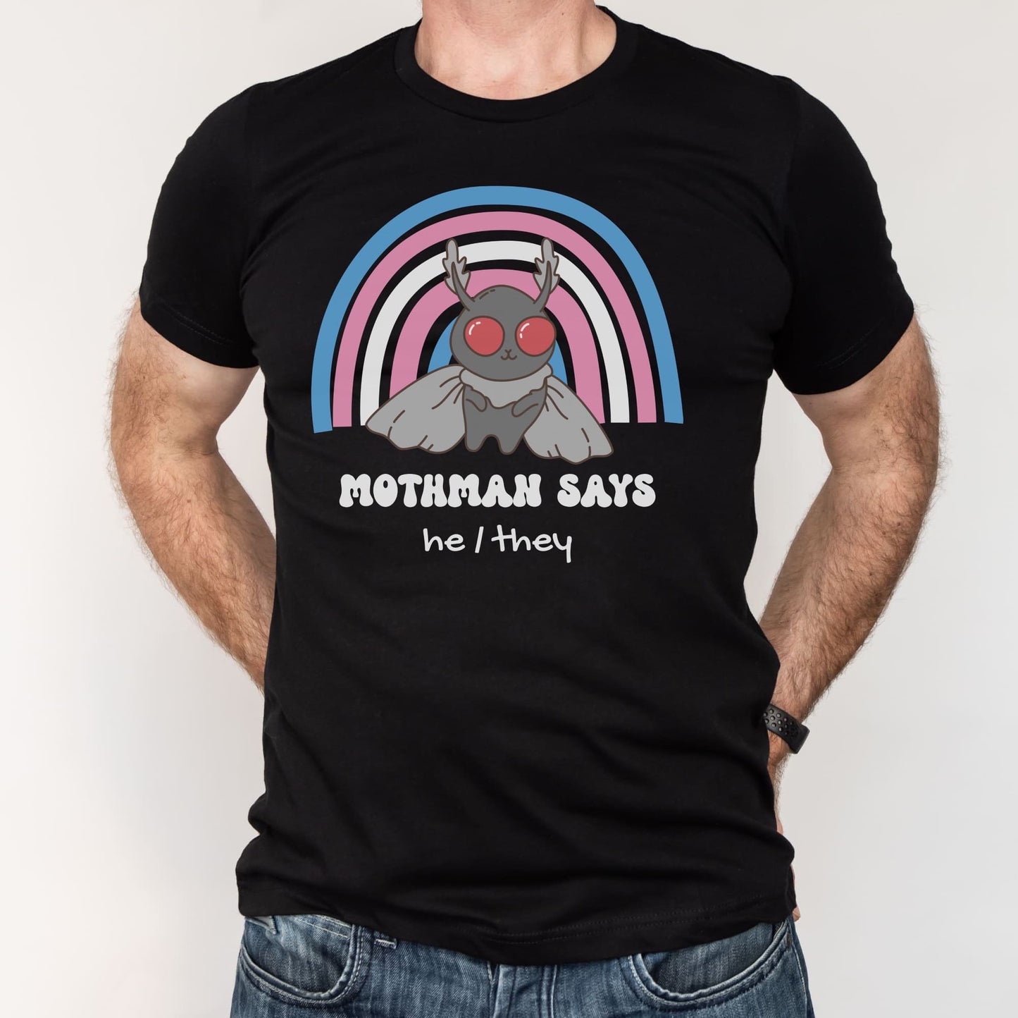 Black t-shirt with Mothman graphic and rainbow arch, worn by a person on a white background: Personalized Trans Mothman Shirt, Custom Pronouns Transgender Pride Cryptid Tee, Folklore Mythology TShirt, Queer Cryptozoology FTM FTM Gift