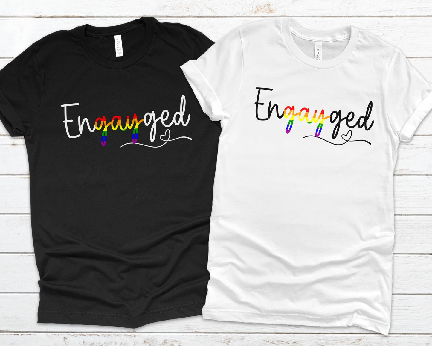 Queer engagement matching t-shirts with 'Engayged' text on a wooden surface