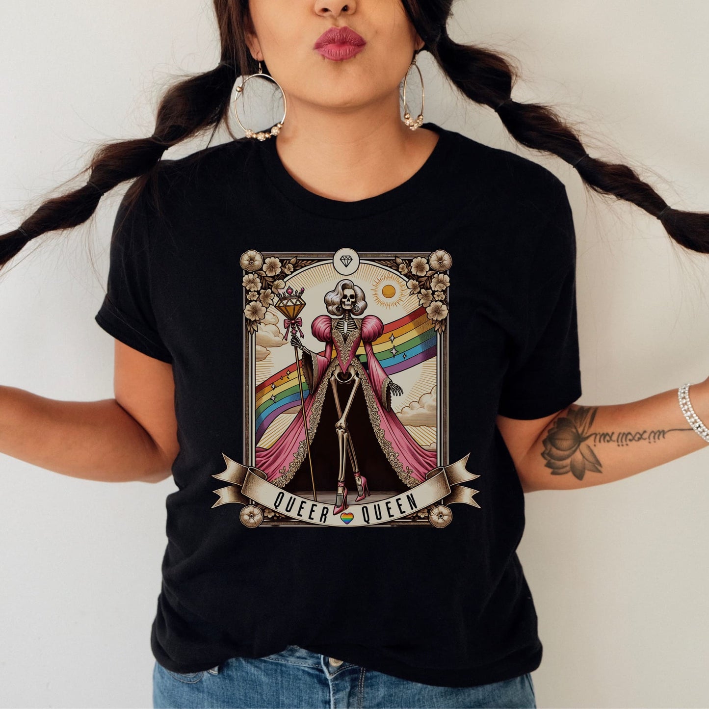 Person wearing a black t-shirt with a graphic design featuring a rainbow flag and text: LGBTQ Queer Queen Shirt, Spooky Gay Skeleton Tarot Card Tee, Whimsical Goth LGBT Pride T-Shirt, Witchy Vibes Tshirt, Funny Occult Gift