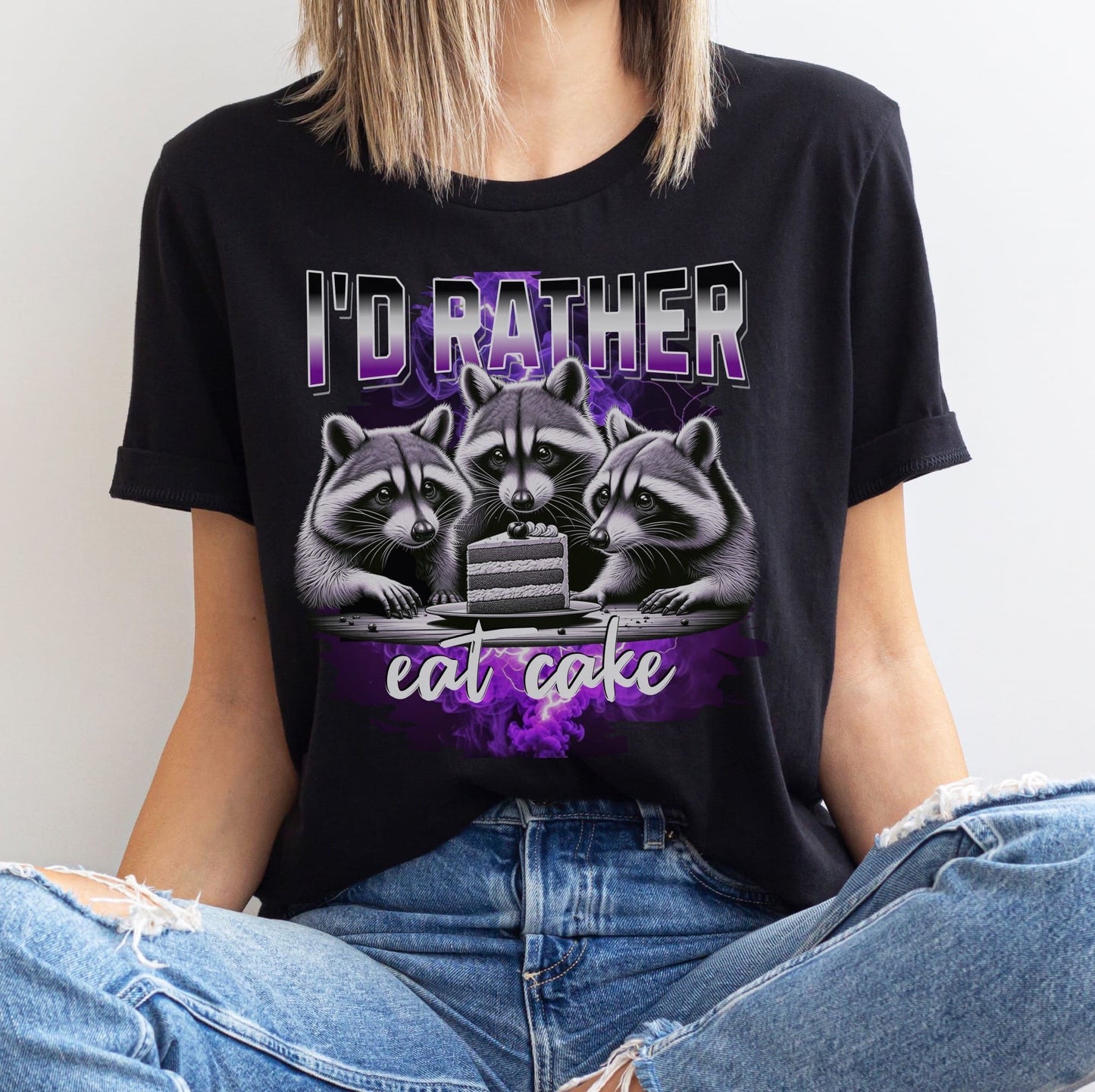 Person wearing a black asexual t-shirt with raccoons and cake y2k bootleg design and text 'I'd rather eat cake'.