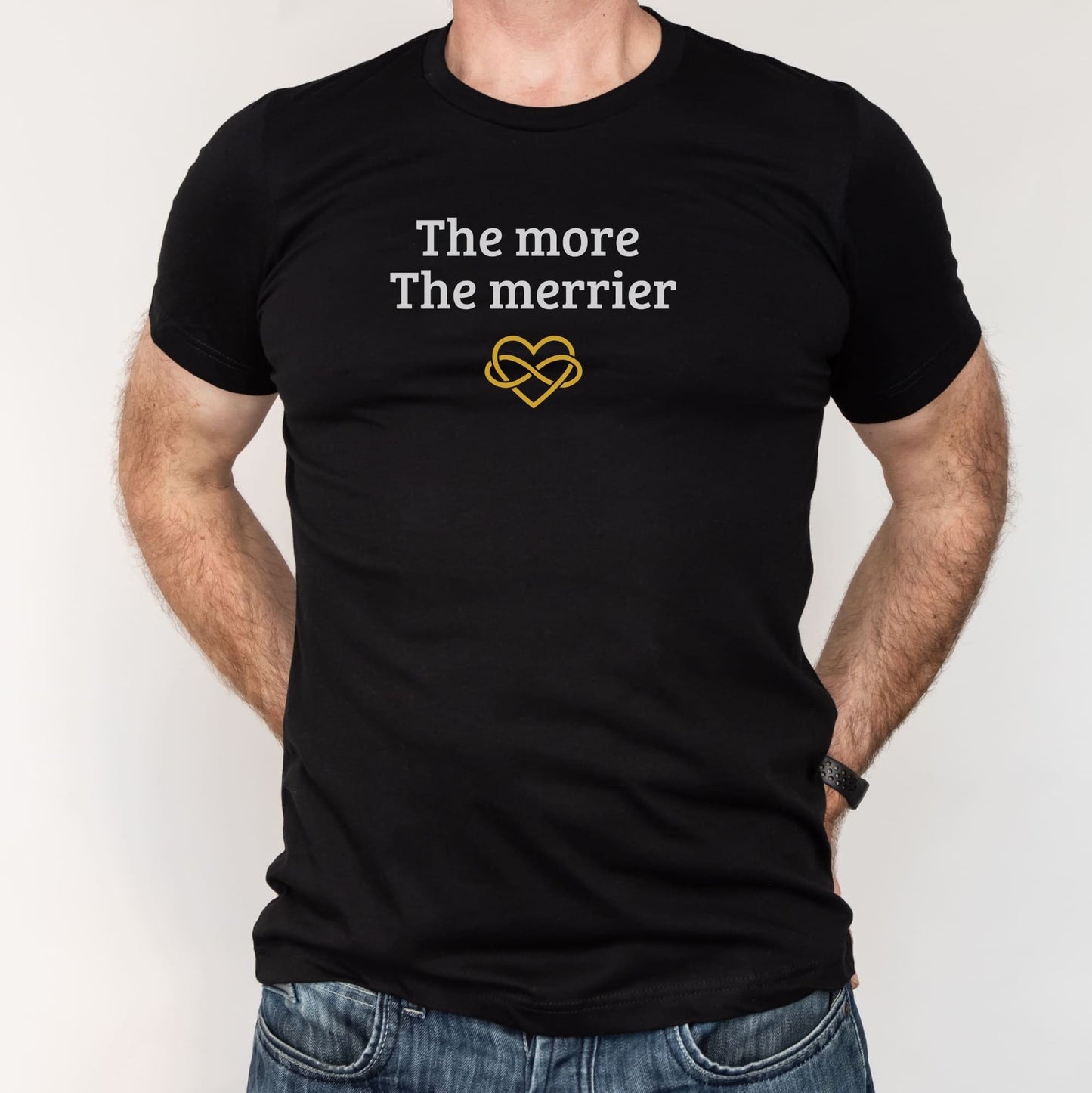 Black t-shirt with 'The more The merrier' text and heart design worn by a person on a white background: Subtle Polyamory Shirt, Funny Open Relationship Tee, Polyamorous Pride T-Shirt, Non Monogamy, Polycule Gift For Big Middle Little Spoon