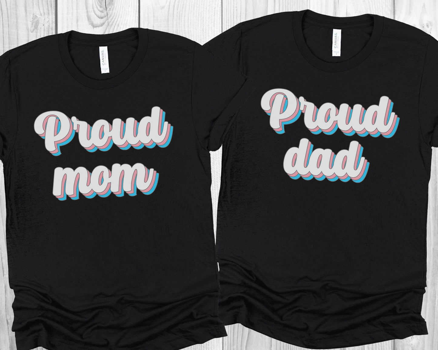 matching transgender t-shirts with 'Proud mom' and 'Proud dad' text on a wooden surface.