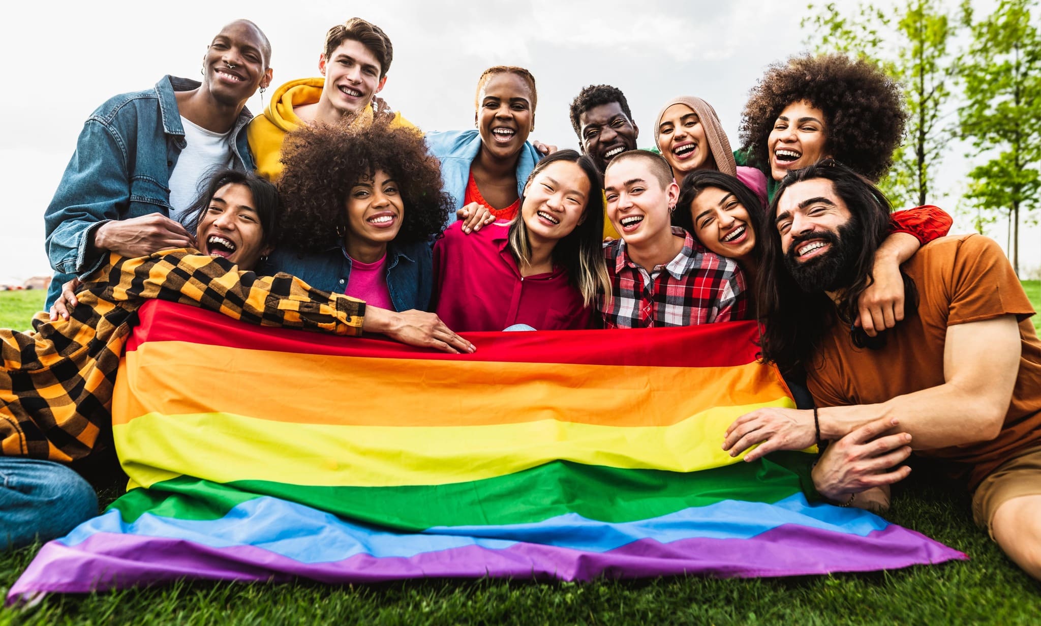 Pride store for LGBTQ clothing & accessories - group of young people holding the rainbow flag