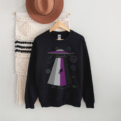 Black asexual sweatshirt with UFO design on a hanger against a white wall.