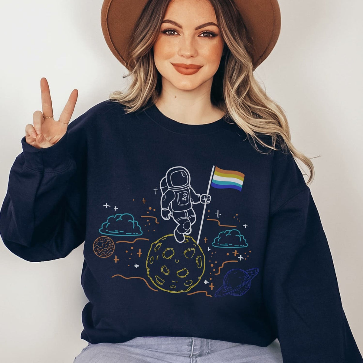 Person wearing a navy blue sweatshirt with an aroace astronaut design on a plain background