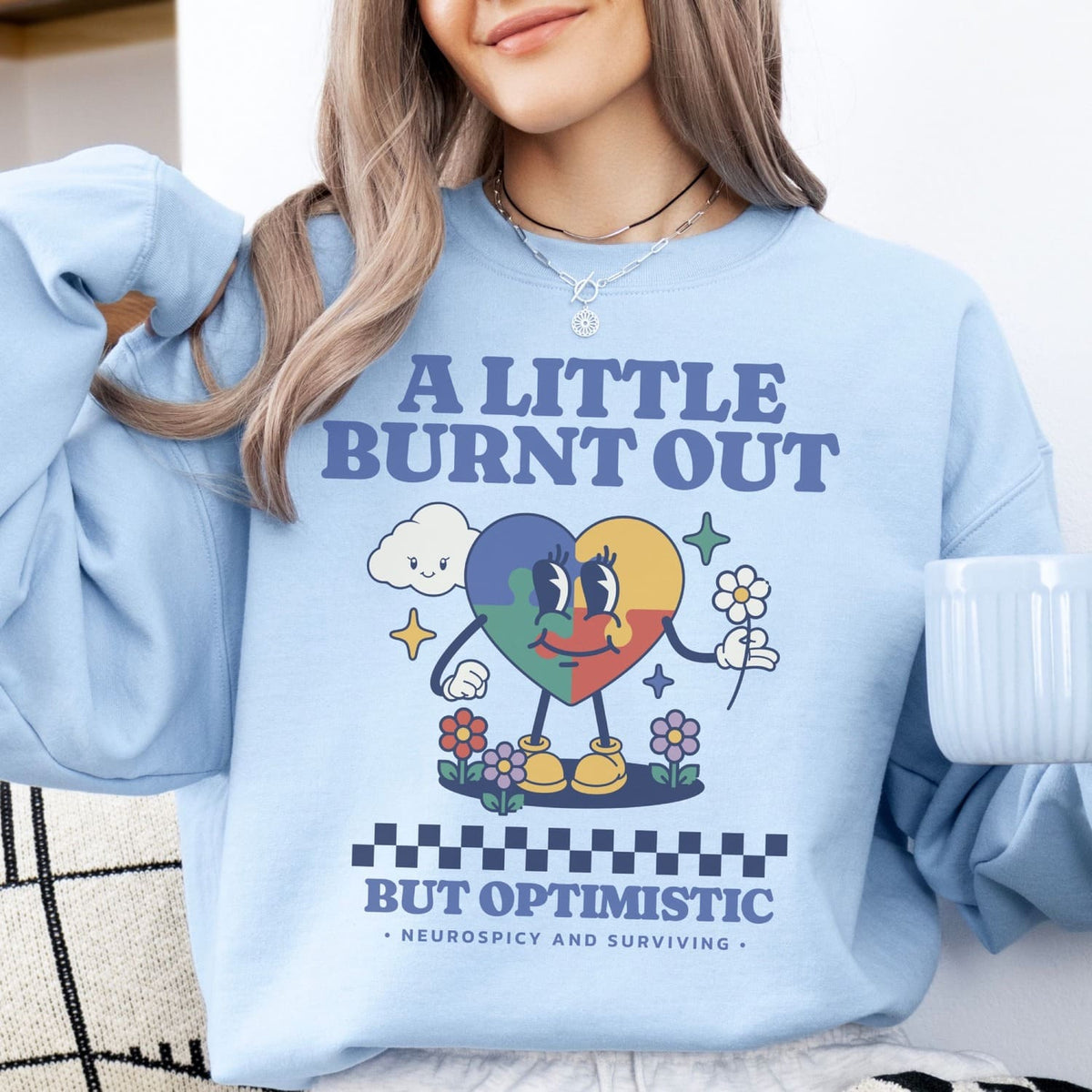 Person wearing a light blue neurodivergent sweatshirt with a colorful graphic and text.