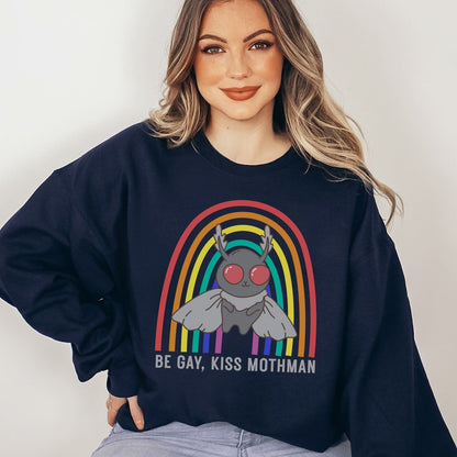 Person wearing a navy sweatshirt with a graphic design of Mothman under a rainbow and text 'Be Gay, Kiss Mothman' on a plain background.