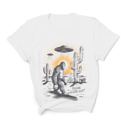 White t-shirt with a graphic of a Sasquatch, UFO, and cactus on a white background