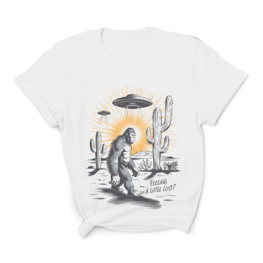 White t-shirt with a graphic of a Sasquatch, UFO, and cactus on a white background