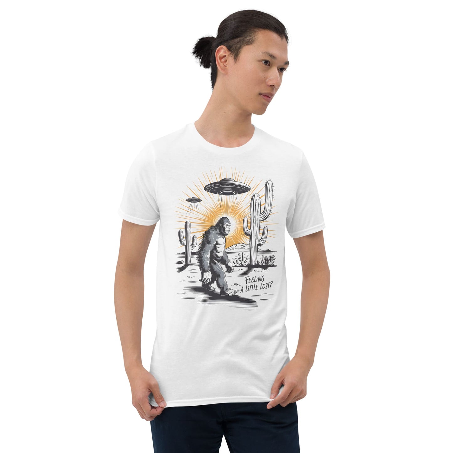 Person wearing a white t-shirt with a graphic design of a UFO over a desert landscape with bigfoot and cacti.