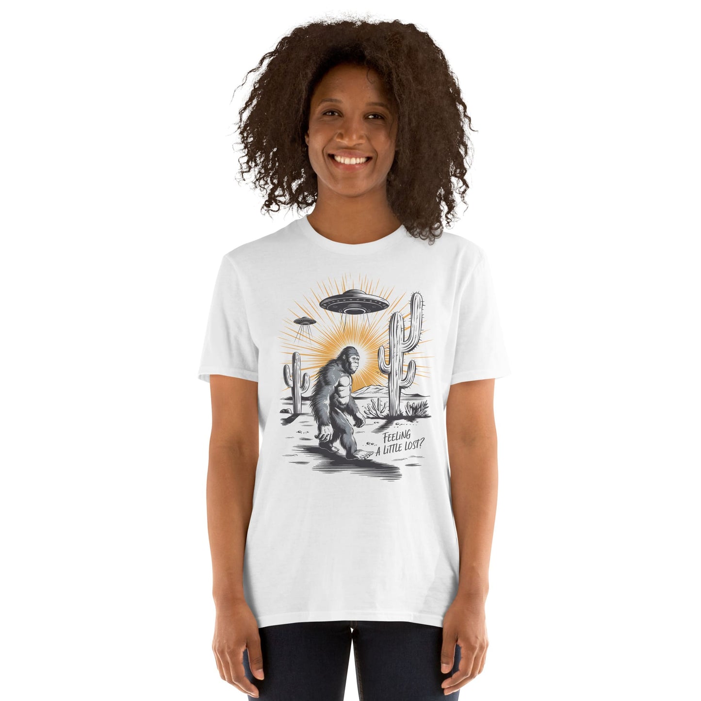 Person wearing a white t-shirt with bigfoot, UFO, and cactus.