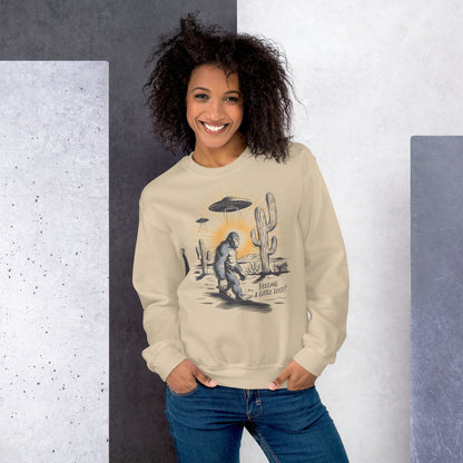 Woman wearing a beige mental health sweatshirt with a graphic design of a Sasquatch, UFO, and cactus.