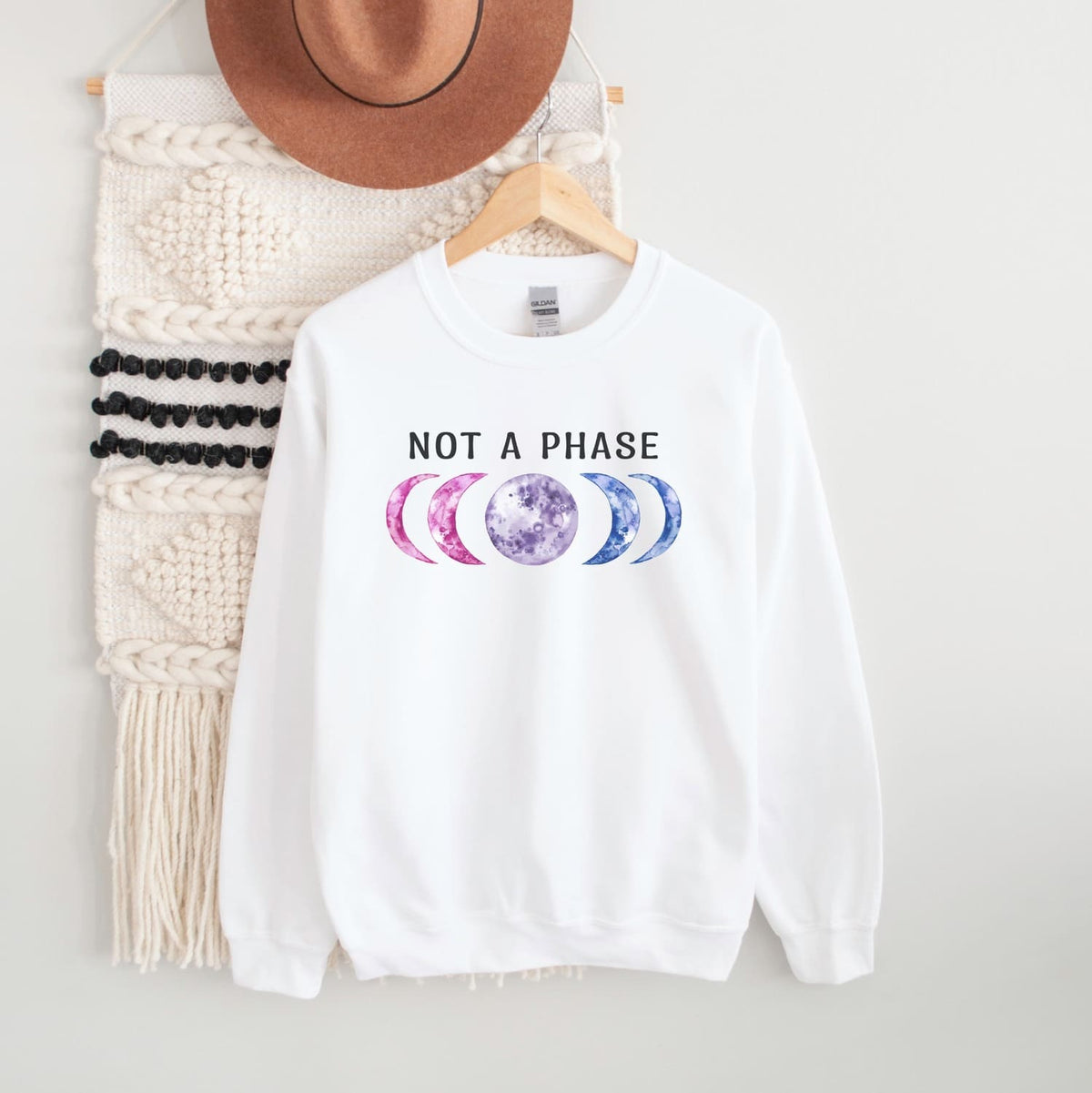 White bisexual sweatshirt with moon phase design and 'Not a Phase' text on a white background
