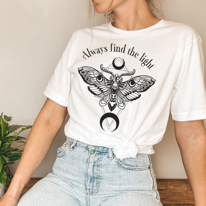 Person wearing a white inspirational t-shirt with a moth design and 'Always find the light' text.