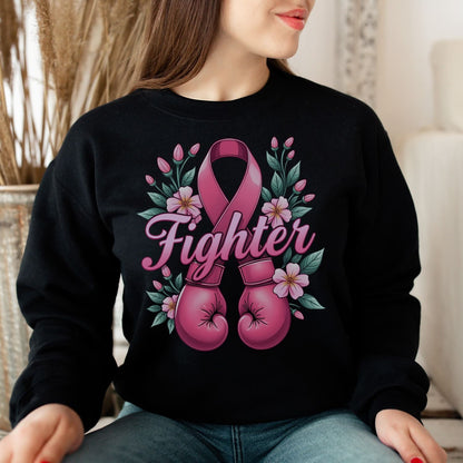 Breast cancer fighter wearing a black sweatshirt with pink boxing gloves and a ribbon design, sitting indoors.