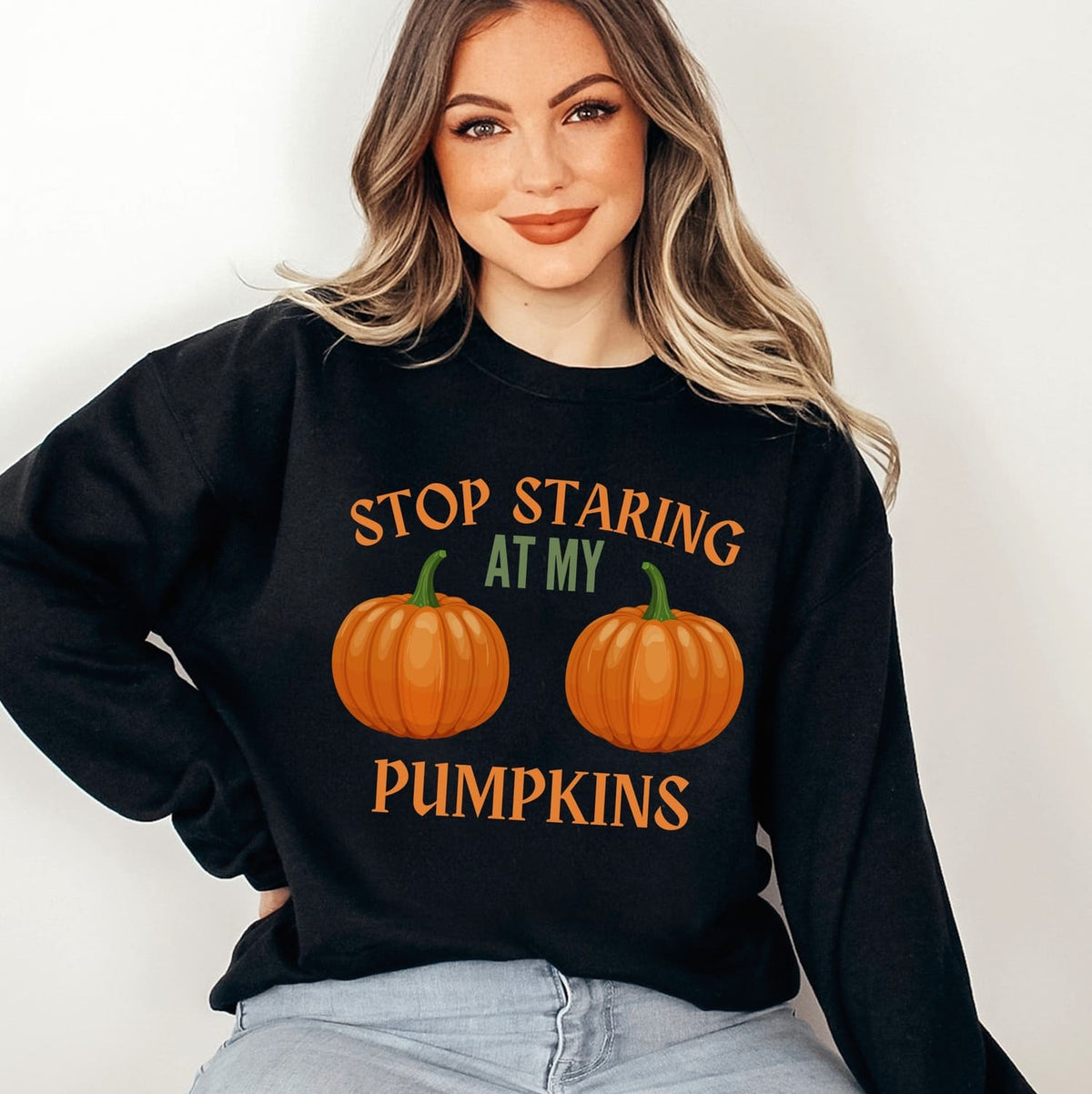 Person wearing a black halloween sweatshirt with pumpkin boobs design and text on a white background