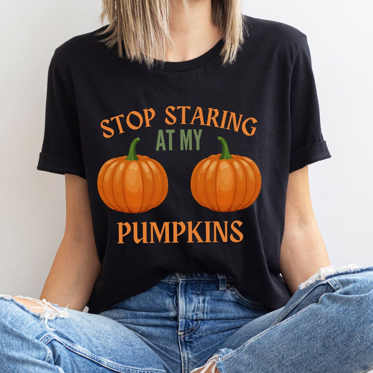 Person wearing a black halloween t-shirt with pumpkin boobs design and text.