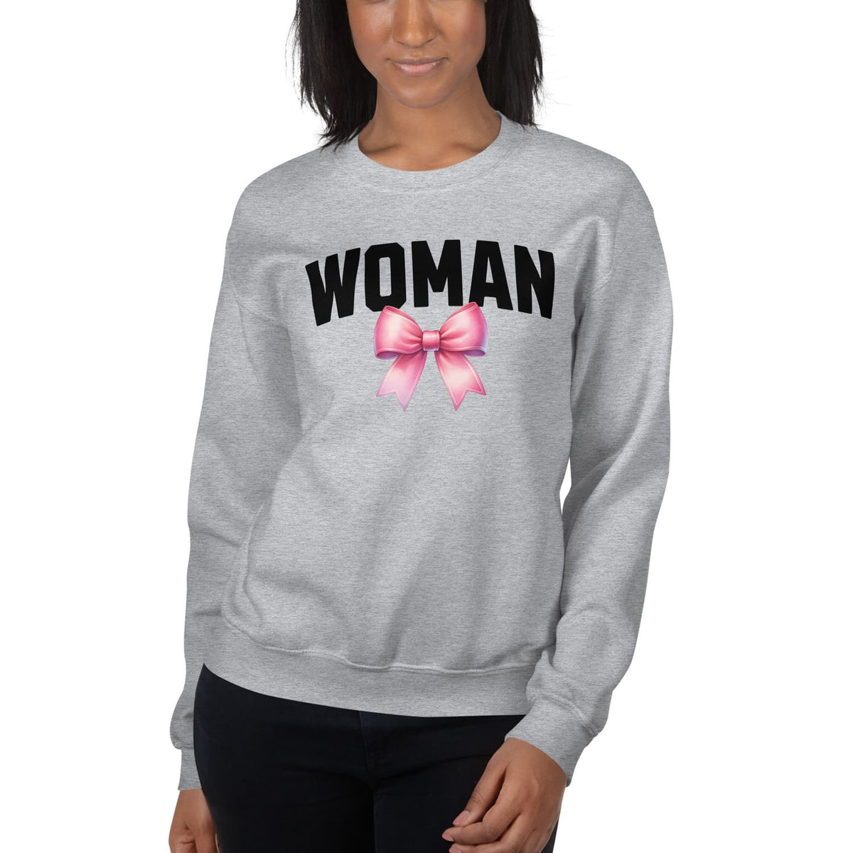 Gray mtf transgender sweatshirt with 'WOMAN' and a pink bow graphic worn by a person on a white background