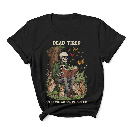 Black t-shirt with a skeleton reading a book surrounded by bunnies and text 'Dead Tired But One More Chapter' on a white background.