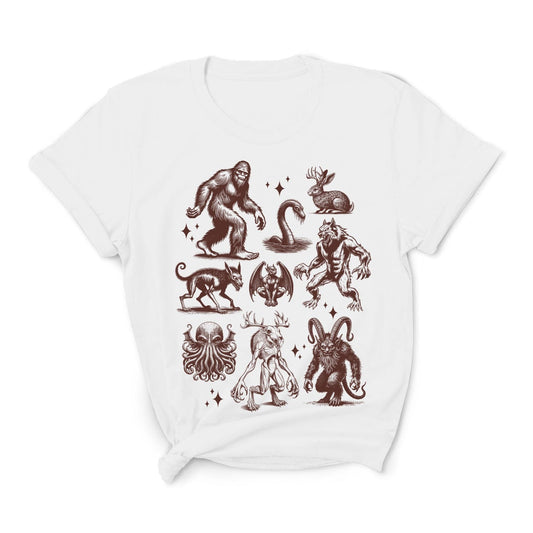 White t-shirt with various mythical creatures like loch ness, wendigo, jackalope, jersey devil, krampus, bigfoot, werewolf, chupacabra, cthulhu, and moreon a white background