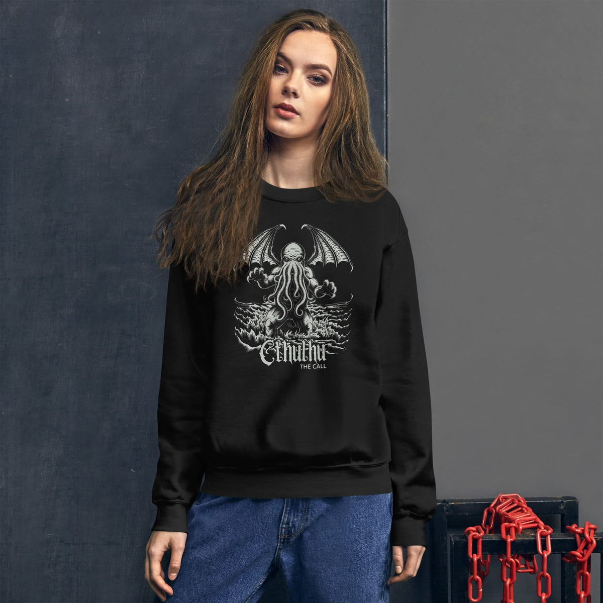 Person wearing a black sweatshirt with a Cthulhu design against a dark background