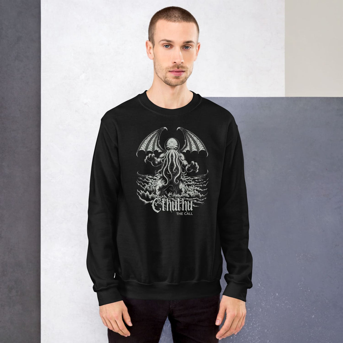 Man wearing a black sweatshirt with cthulhu against a gray background