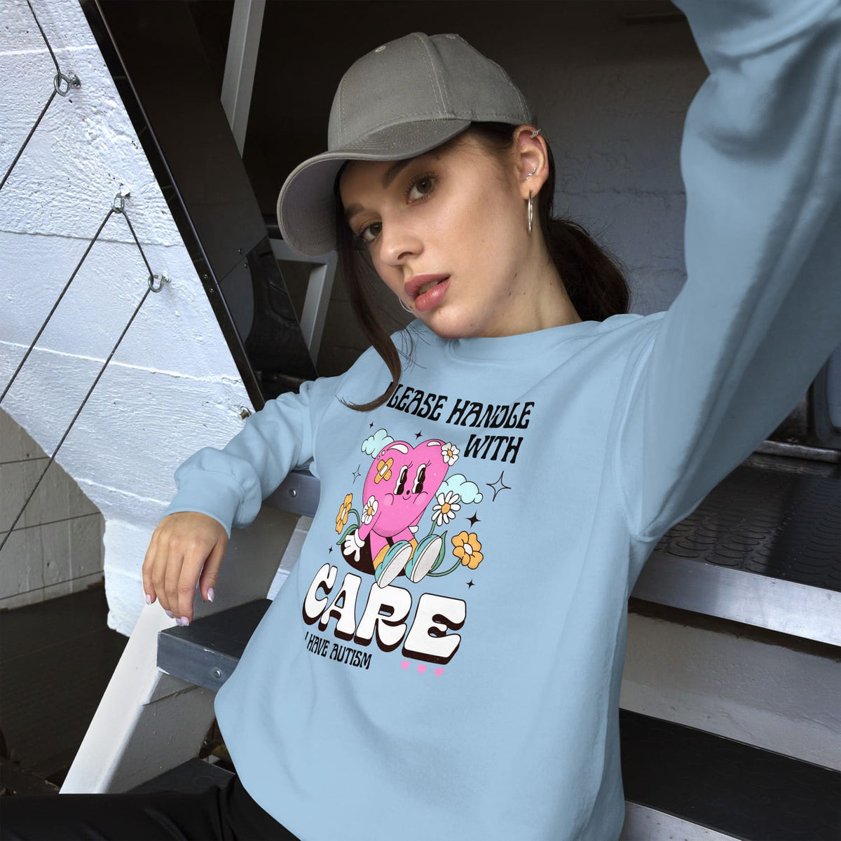Person wearing a light blue autism sweatshirt with a graphic design and text, sitting on stairs.