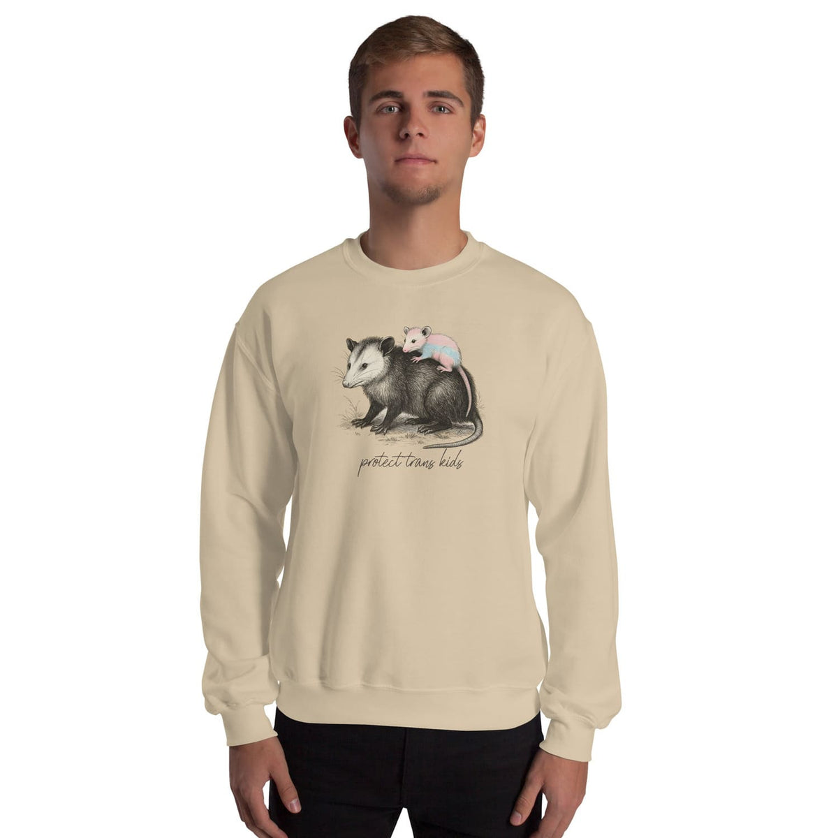 Person wearing a beige 'protect trans kids' sweatshirt with a graphic of two opossums and text on a white background