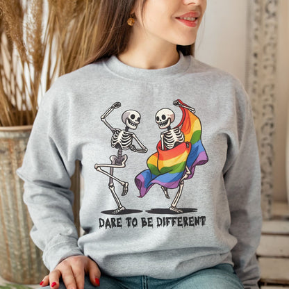 Person wearing a gray lgbt sweatshirt with skeletons dancing and a rainbow flag, with text 'Dare to be different'.