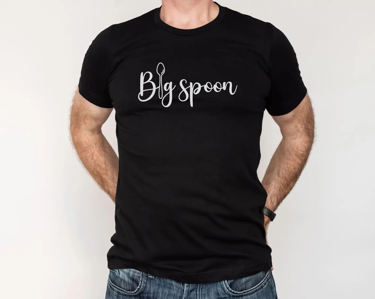 Polyamorous person wearing a black t-shirt with 'Big spoon' ENM text on a plain background