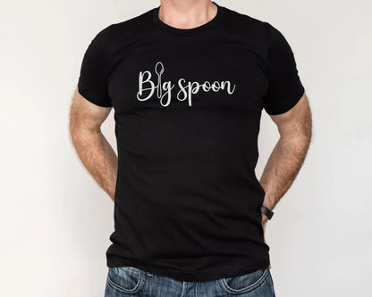 Polyamorous person wearing a black t-shirt with 'Big spoon' ENM text on a plain background