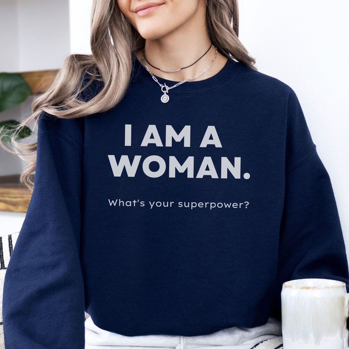 Person wearing a navy blue feminist  sweatshirt with text 'I AM A WOMAN. What's your superpower?'