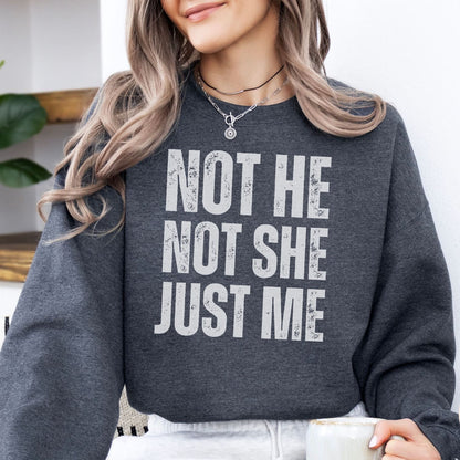 Person wearing a dark gray non binary sweatshirt with 'Not He, Not She, Just Me' text.