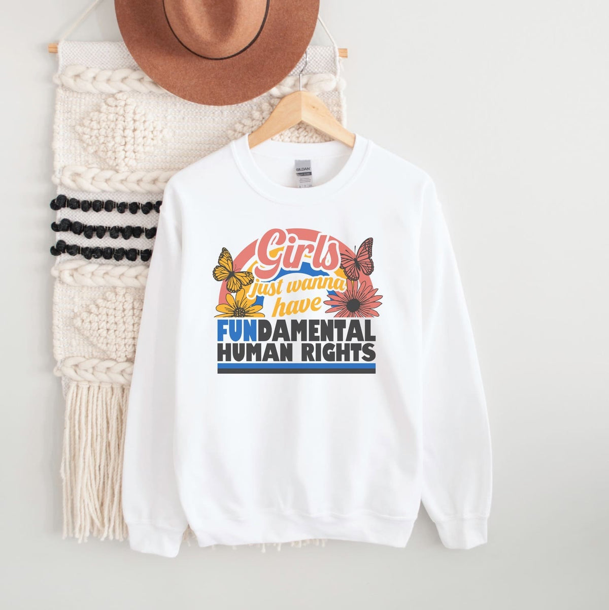 White feminist sweatshirt with colorful text and butterfly graphics on a hanger with a white background