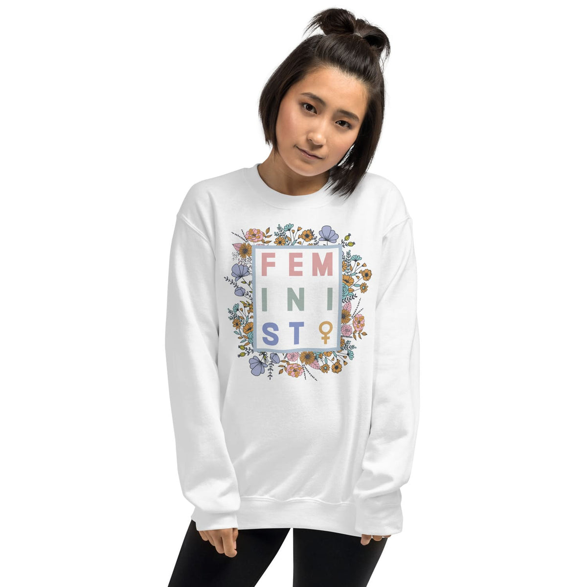 Person wearing a white sweatshirt with floral 'FEMINIST' design on a white background