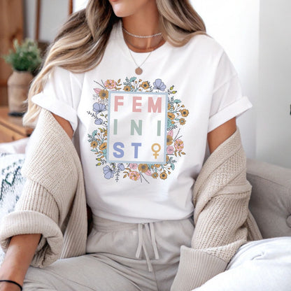 Person wearing a white t-shirt with floral 'FEMINIST' design in the center.
