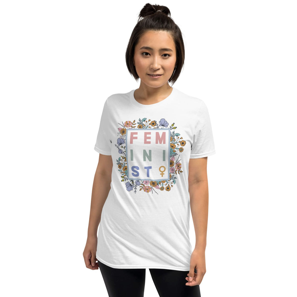 Person wearing a white t-shirt with floral 'FEMINIST' design on a plain background