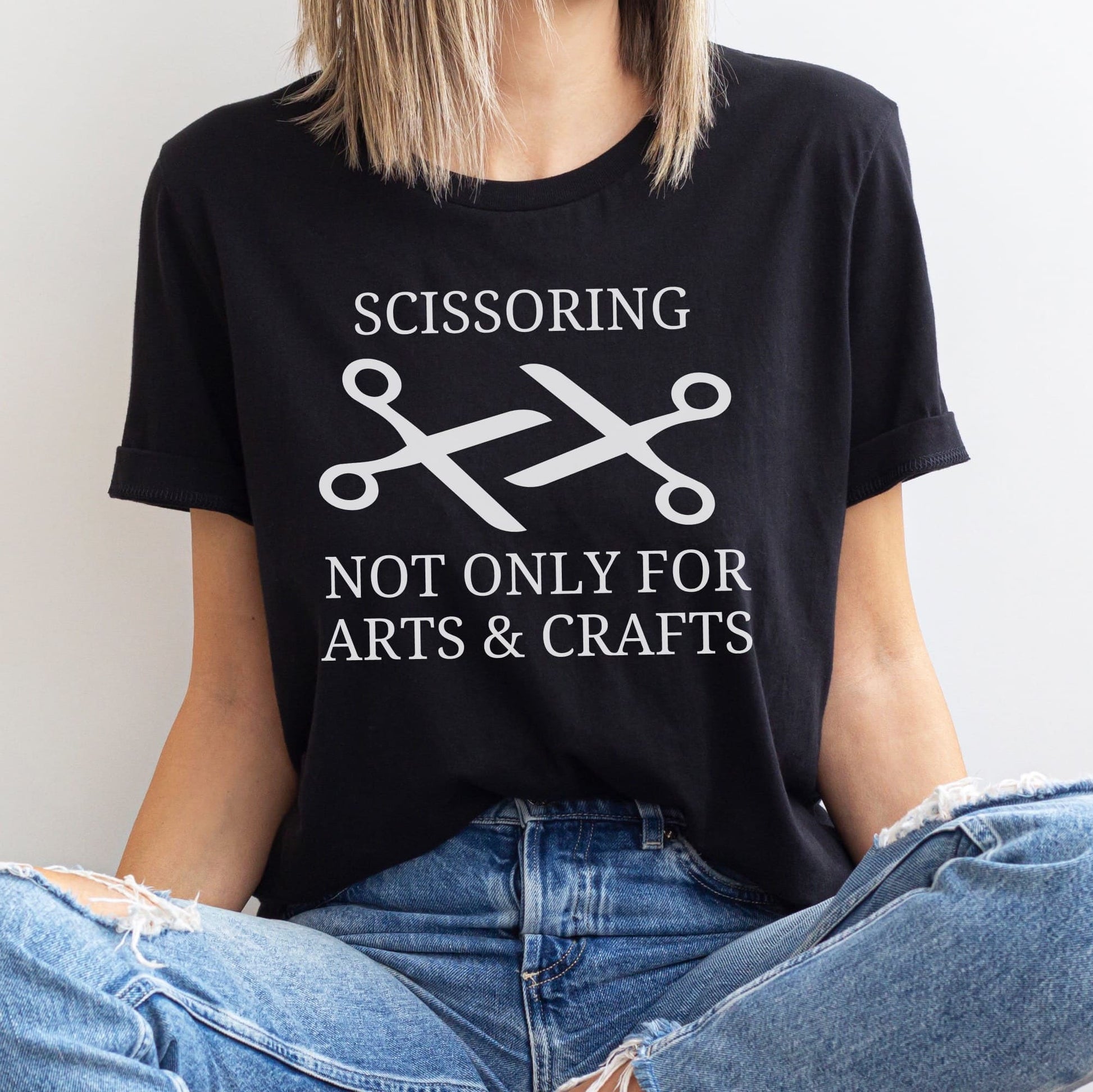 Person wearing a lesbian wlw black t-shirt with a graphic and text 'SCISSORING NOT ONLY FOR ARTS & CRAFTS'.
