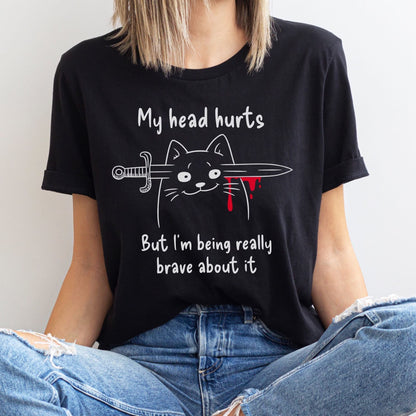 Person wearing a black t-shirt with a graphic of a cat holding a sword and text, sitting against a white background: My Head Hurts Shirt, Headache Tee, Chronic Migraine Warrior, Morbid Cat Meme, Funny Spoonie Gift, Mental Illness T-Shirt, Dark Humor