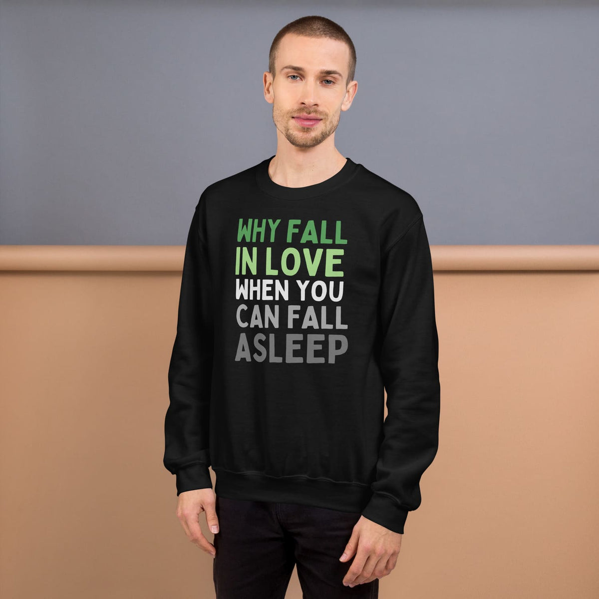 Man wearing a black aromantic sweatshirt with humorous text design against a neutral background