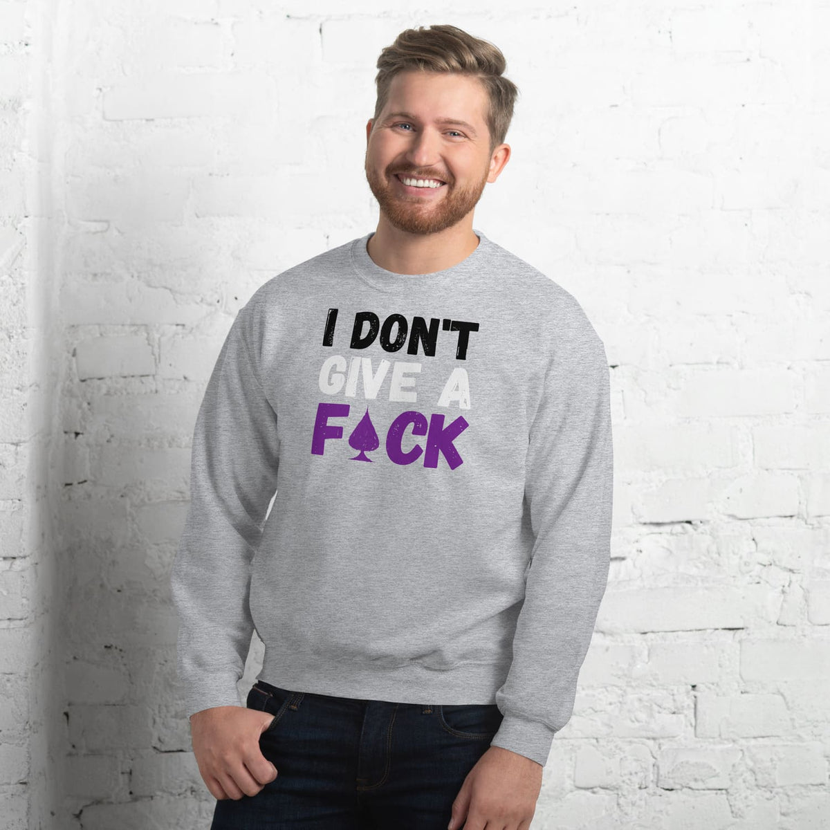 Man wearing a gray asexual sweatshirt with text in front of a white brick wall