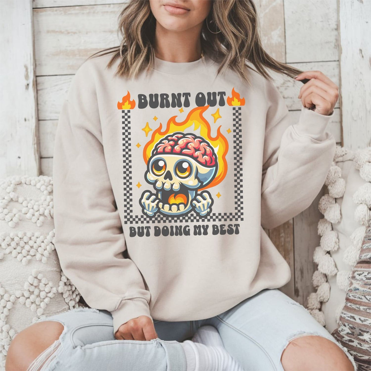 Person wearing a beige burnout sweatshirt with a graphic design featuring a skull and flames.